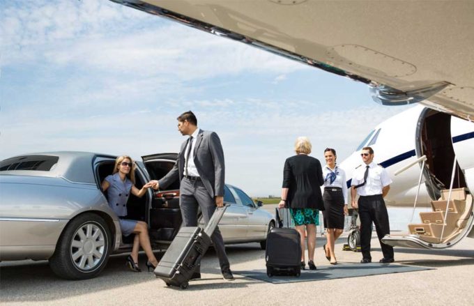 Business professionals exiting vehicle about to board private jet