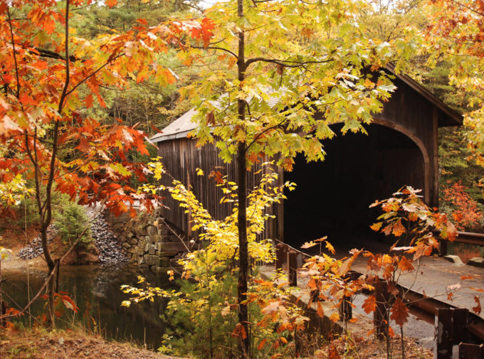 Covered bridge surrounded by fall foliage.