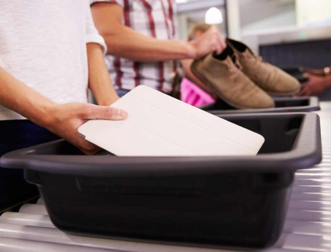 Passenger placing his tablet in airport security tray.