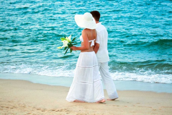 Couple enjoying a romantic walk on the beach after their destination wedding by private plane to Nassau, Bahamas.